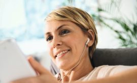 Femme allongée écoutant de la musique avec des écouteurs filaires