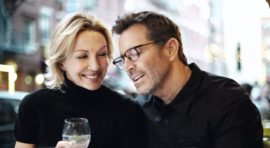 Couple attablé en terrasse, un verre à la main, en pleine conversation
